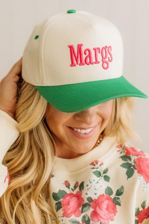 Person wearing a cap with 'Margs' on it, smiling.