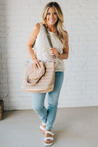 Woman holding a mocha nylon quilted traveler tote bag.