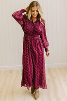 Blonde woman in a brightly lit studio wearing boots and a long dark red dress with full button front and pintucked bodice.