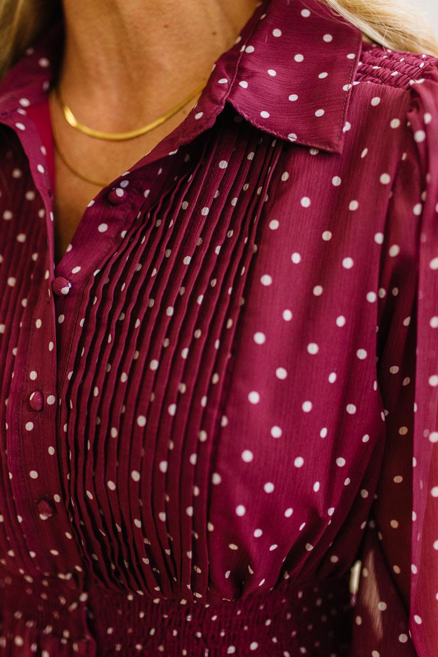 Blonde woman in a brightly lit studio wearing boots and a long dark red dress with full button front and pintucked bodice.