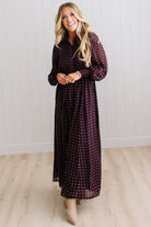 Blonde woman in a brightly lit studio wearing boots and a long dark purpleish brown dress with full button front and pintucked bodice.