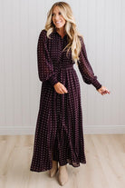 Blonde woman in a brightly lit studio wearing boots and a long dark purpleish brown dress with full button front and pintucked bodice.