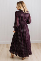 Blonde woman in a brightly lit studio wearing boots and a long dark purpleish brown dress with full button front and pintucked bodice.