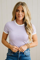 Woman wearing a striped shirt and jeans against a plain background