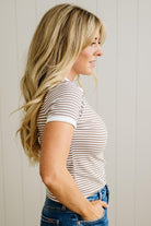 Woman wearing a striped shirt and jeans against a plain background