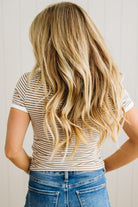 Person with long blonde hair wearing a striped shirt and blue jeans against a plain background
