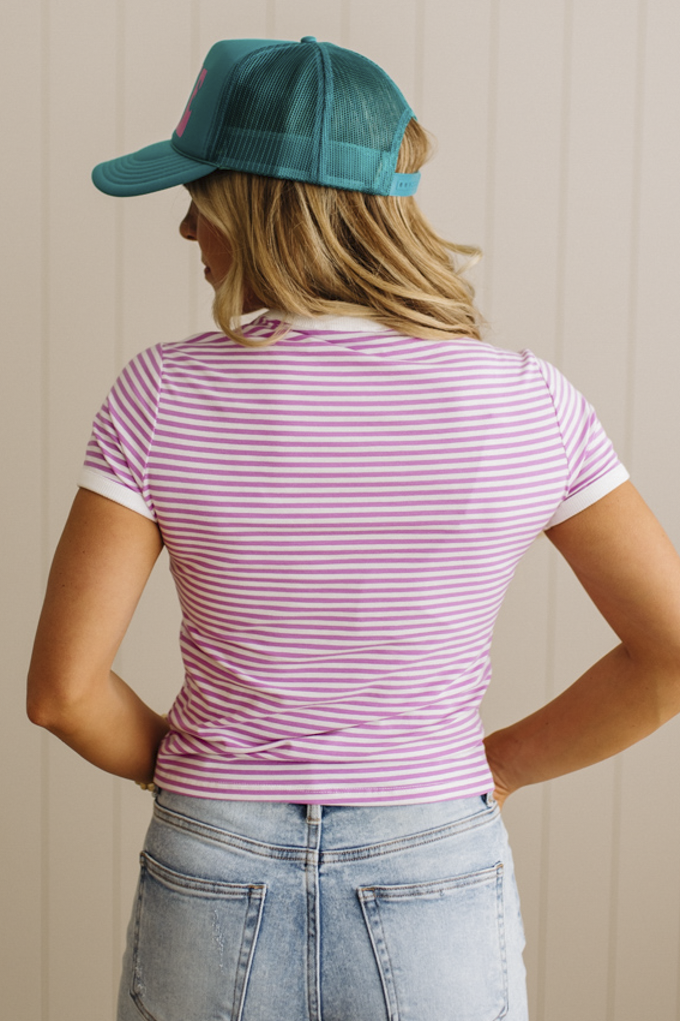 Person wearing a striped shirt and cap with a neutral background