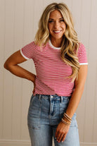 Woman wearing a red and white striped shirt and blue jeans against a neutral background