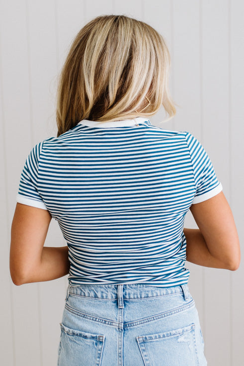 Person wearing a blue and white striped shirt and light blue jeans against a plain background