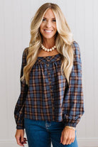 Blonde woman in a brightly lit studio wearing a PLAID SQUARE NECK BUTTON CLOSURE FRONT LONG SLEEVE BLOUSE  WITH DARK JEANS AND BROWN BOOTS.