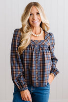 Blonde woman in a brightly lit studio wearing a PLAID SQUARE NECK BUTTON CLOSURE FRONT LONG SLEEVE BLOUSE  WITH DARK JEANS AND BROWN BOOTS.