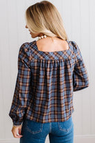 Blonde woman in a brightly lit studio wearing a PLAID SQUARE NECK BUTTON CLOSURE FRONT LONG SLEEVE BLOUSE  WITH DARK JEANS AND BROWN BOOTS.