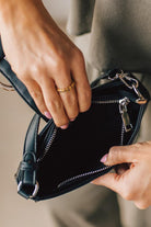 Woman holding a small black handbag with large silver buckle accent and silver hardware