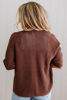 Person wearing a brown textured sweater with a neutral background