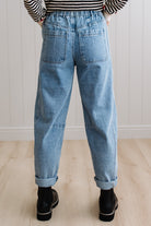Person wearing light blue denim pants with a paneled wall background