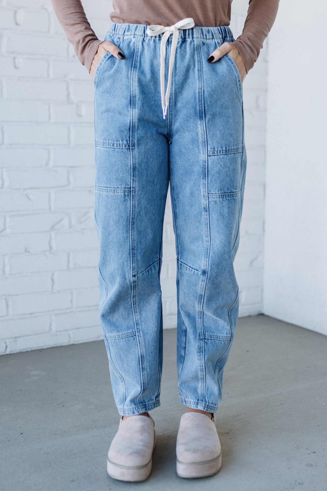 Person wearing blue patchwork jeans with a white brick wall background