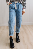 Person wearing light blue denim pants with a paneled wall background