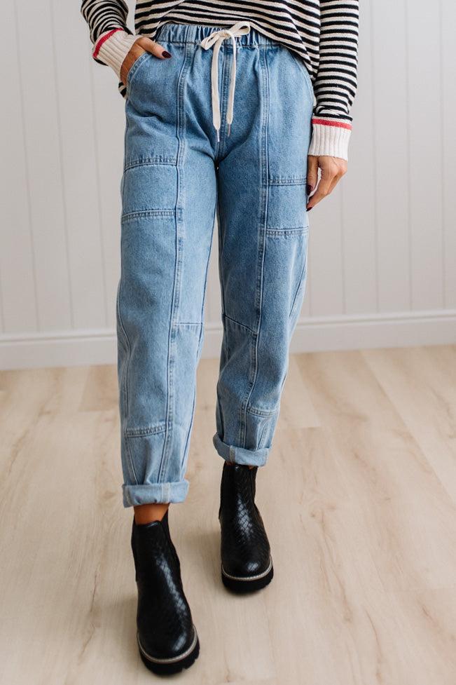 Person wearing light blue denim pants with a paneled wall background