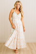 Woman wearing a floral dress against a white paneled wall.