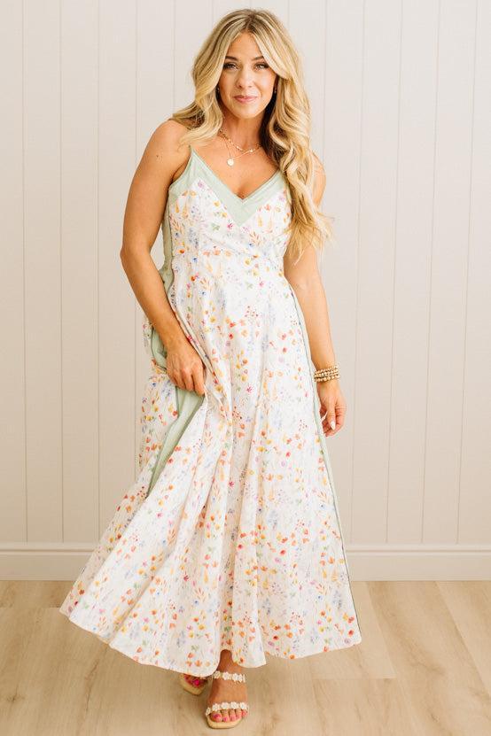 Woman wearing a floral dress against a white paneled wall.