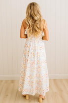 Woman wearing a floral dress standing against a white wall.