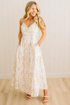 Woman wearing a floral dress against a white paneled wall.