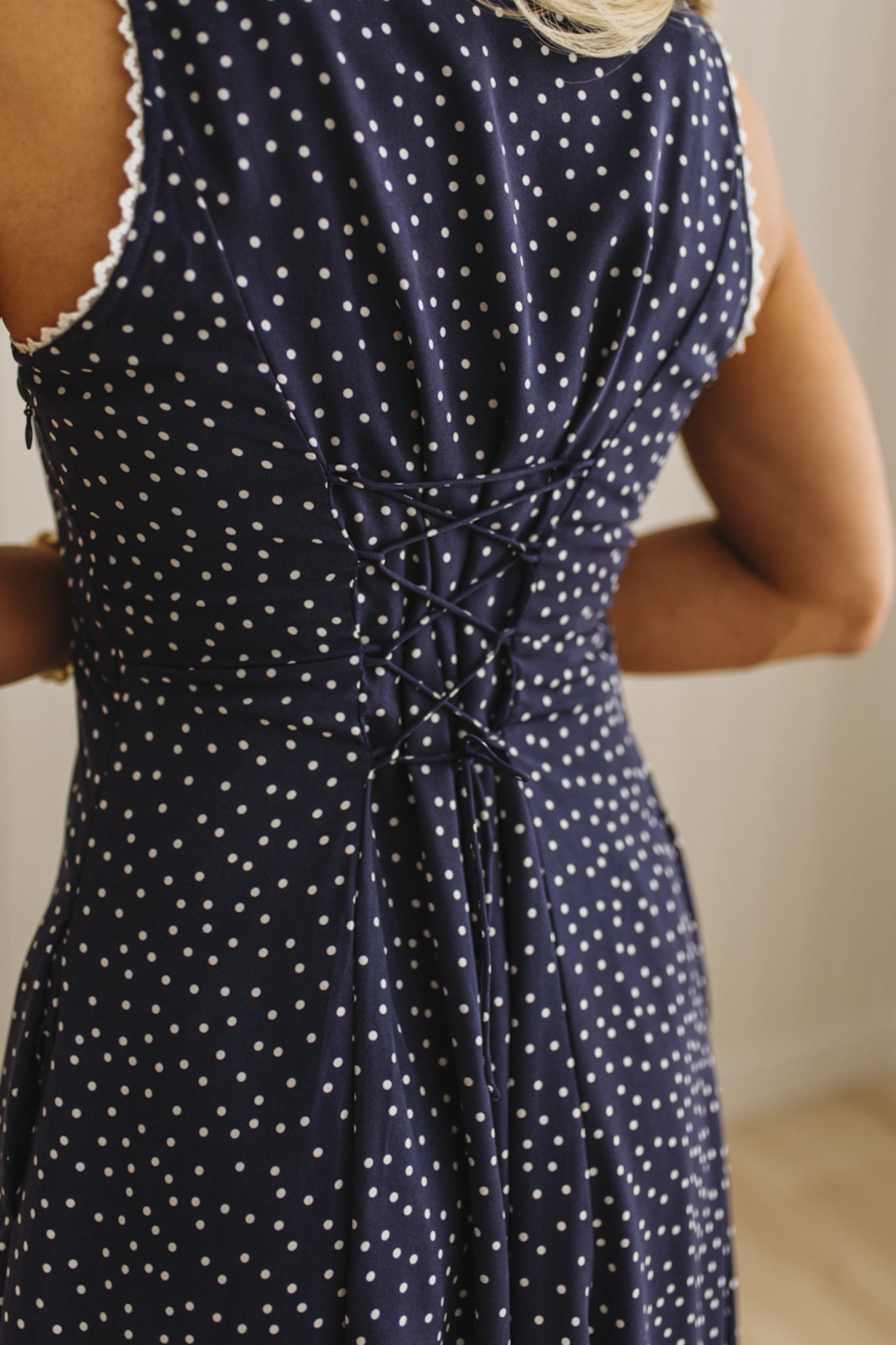 Navy dress with white polka dots and lace trim on a neutral background