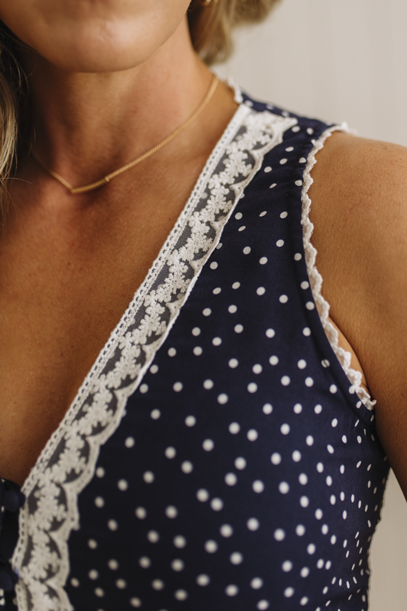 Navy blue top with white polka dots and lace trim on a neutral background