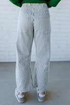 Woman wearing grey and cream vertical stiriped barrel cut jeans with a drawstring waist.