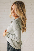 Woman wearing a gray cardigan against a light brick wall
