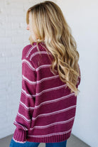 Woman wearing a maroon and white striped sweater against a white background