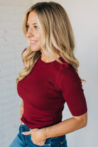 Woman wearing a red top and blue jeans against a plain background