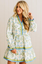 Woman wearing a floral dress with long sleeves against a wooden panel background