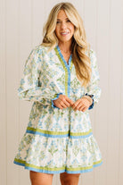 Woman wearing a floral dress with long sleeves against a wooden panel background