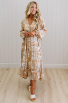 Woman wearing a floral dress standing against a white paneled wall.