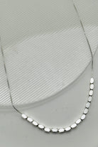 Silver necklace with oval beads on a light gray background