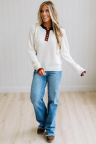 Blonde woman modeling an oat sweater with navy collar, mocha cuffs, and a mocha henlwy with multi color sweater covered buttons. Standing on a light wood floor with light backdrop.