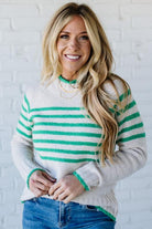 Woman wearing a striped sweater with a white brick wall background