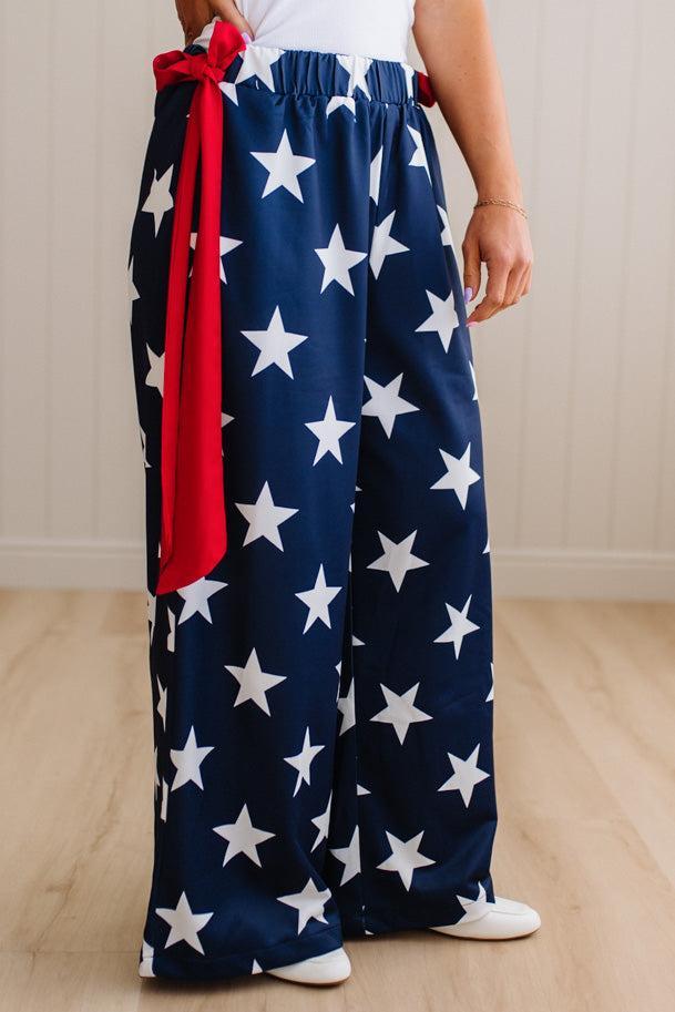 Person wearing a pair of wide-leg pants with star pattern and a red sash.