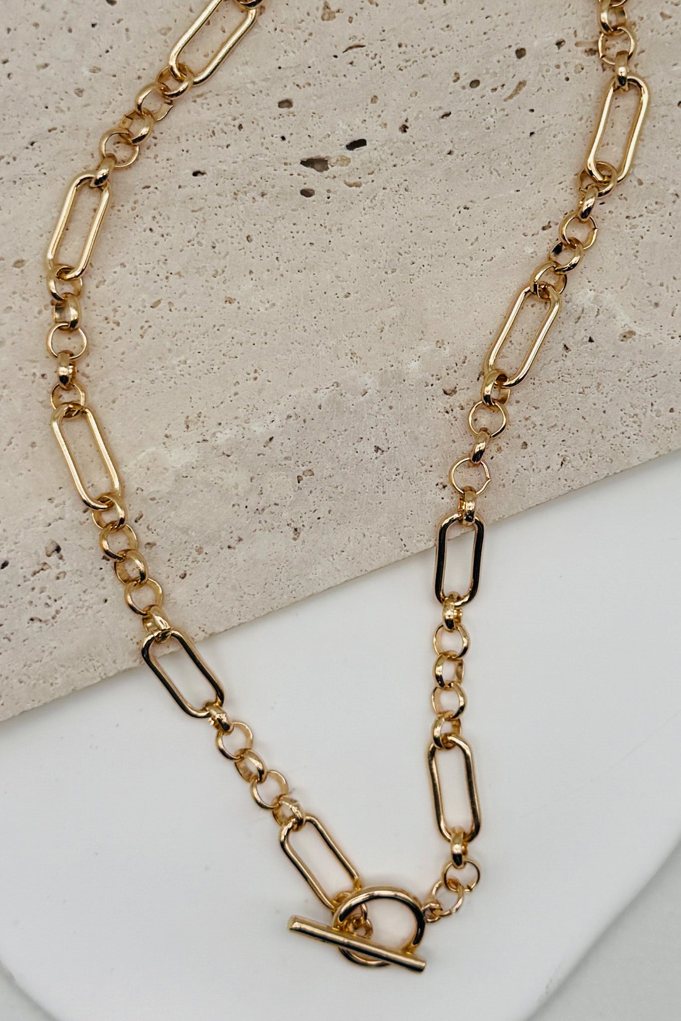 Gold chain necklace on a textured surface
