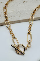 Gold chain necklace with a unique clasp design on a light background