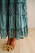 Teal lace dress with ruffled layers on a neutral background
