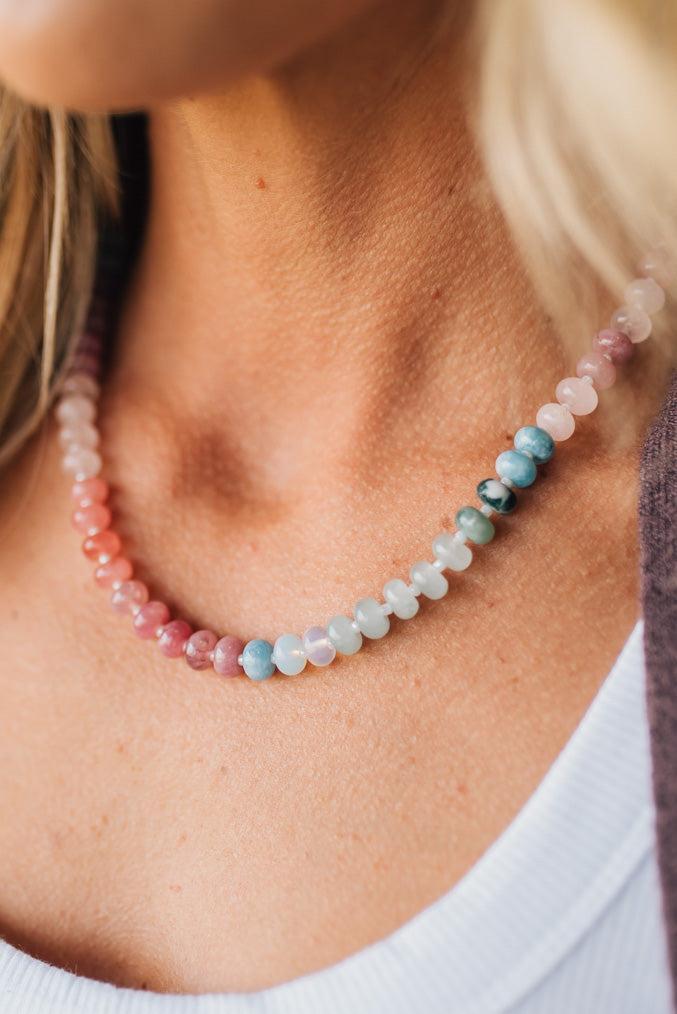 Close-up of a person wearing a beaded necklace with multicolored beads.