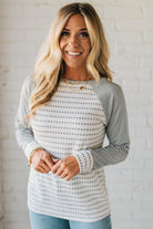 Woman wearing a striped sweater against a white brick wall