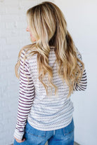 Woman wearing a striped long-sleeve top and jeans against a white background