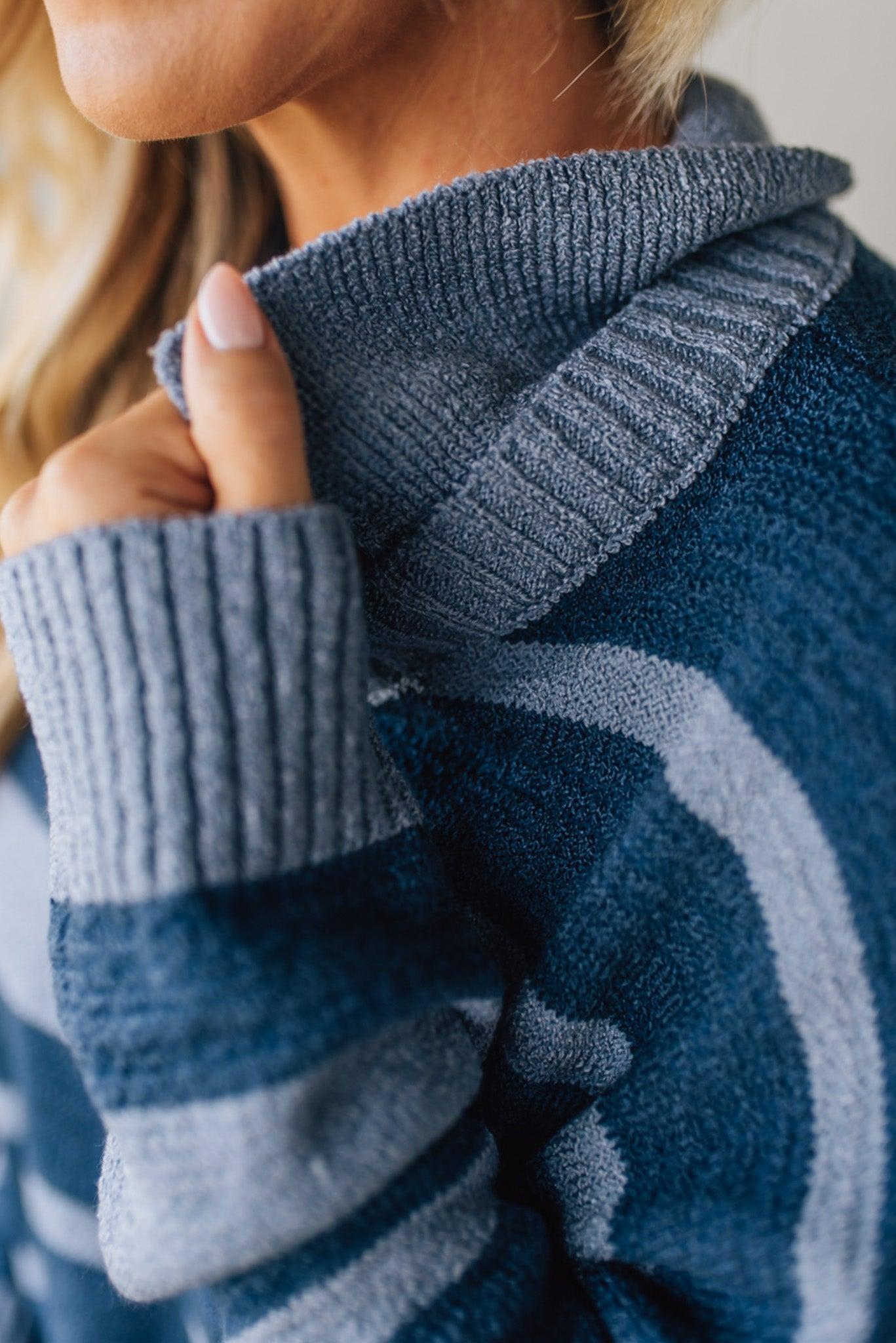 Close-up of a person wearing a blue knitted sweater with a blurred background