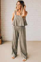 Blonde woman wearing a tank style olive linen blend wide leg jumpsuit with wide leg, pockets, and a square neckline.