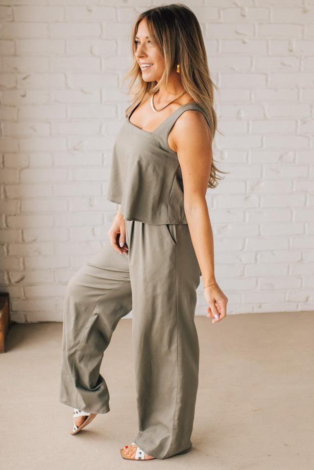 Blonde woman wearing a tank style olive linen blend wide leg jumpsuit with wide leg, pockets, and a square neckline.