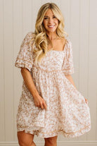 Woman wearing a floral dress against a neutral background