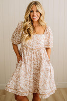 Woman wearing a floral dress against a neutral background